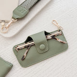 Green phone case with keychain and glasses holder on a textured white surface