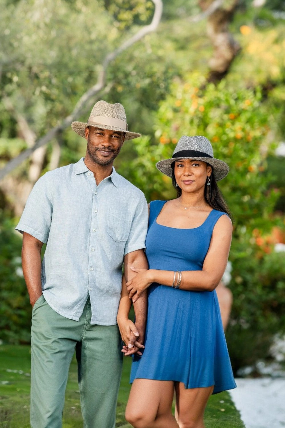 Man wearing a beige hat with a woman wearing a black hat in an outdoor setting