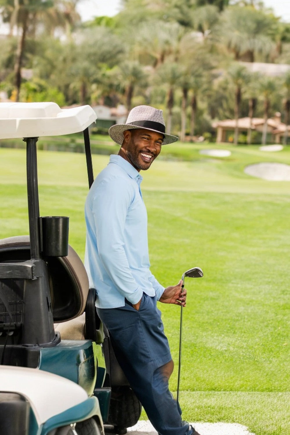 Man on a golf course with a golf cart and club