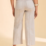 Person wearing a grey wide leg jean with a pink top on a beige background