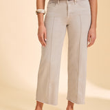 Person wearing a grey wide leg jean with a pink top on a beige background