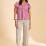 Person wearing a grey wide leg jean with a pink top on a beige background
