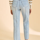 Person wearing striped sweater with blue jeans on beige background