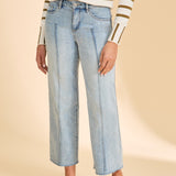 Person wearing striped sweater with blue jeans on beige background