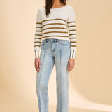 Person wearing striped sweater with blue jeans on beige background