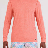 Person wearing a coral hoodie and patterned shorts on a white background