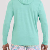 Person wearing a light blue hoodie and patterned shorts on a plain background