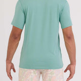Person wearing a light green t-shirt and patterned shorts on a white background