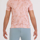 Man wearing a pink floral polo shirt and light blue shorts on a white background