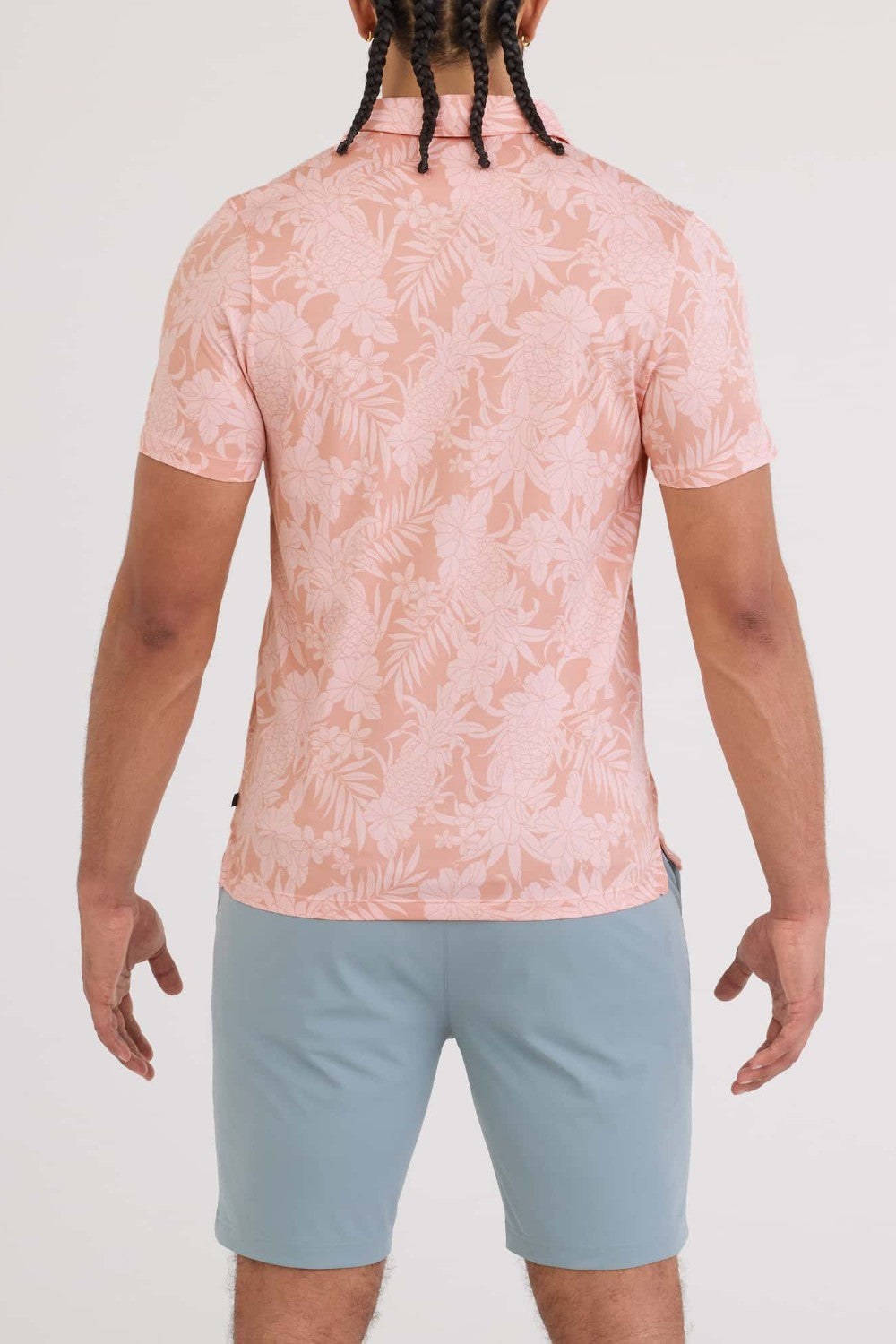 Person wearing a pink floral shirt and light blue shorts on a white background