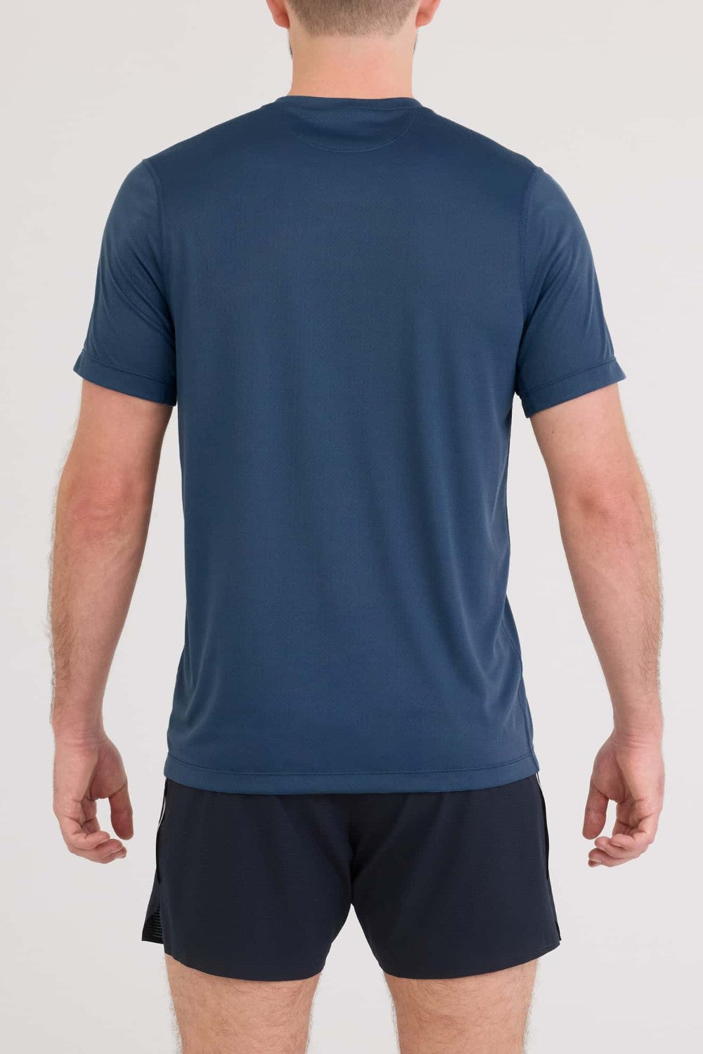 Person wearing a blue athletic shirt and black shorts on a white background