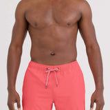 Man wearing pink swim shorts on a white background