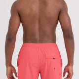 Person wearing coral swim shorts on a white background