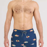 Man wearing navy blue swim shorts with colorful fish pattern on a white background