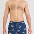 Man wearing navy blue swim shorts with colorful fish pattern on a white background