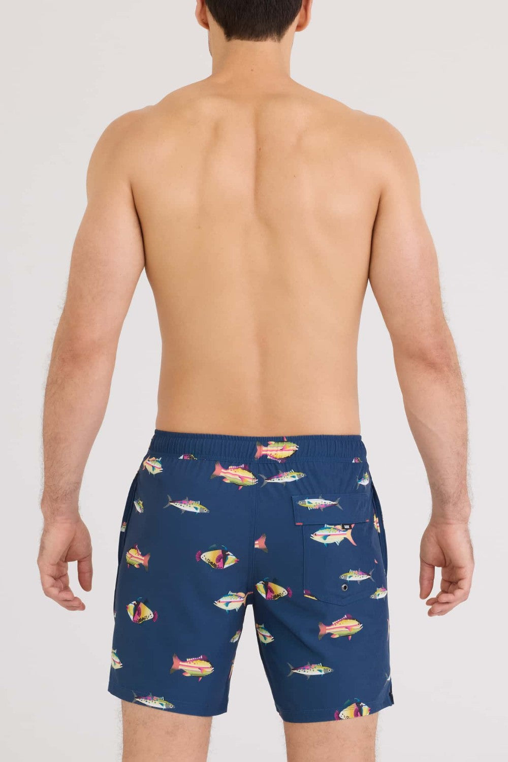 Man wearing navy blue swim shorts with colorful fish pattern on a white background