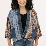 Woman wearing a colorful jacket over a black shirt and jeans on a white background
