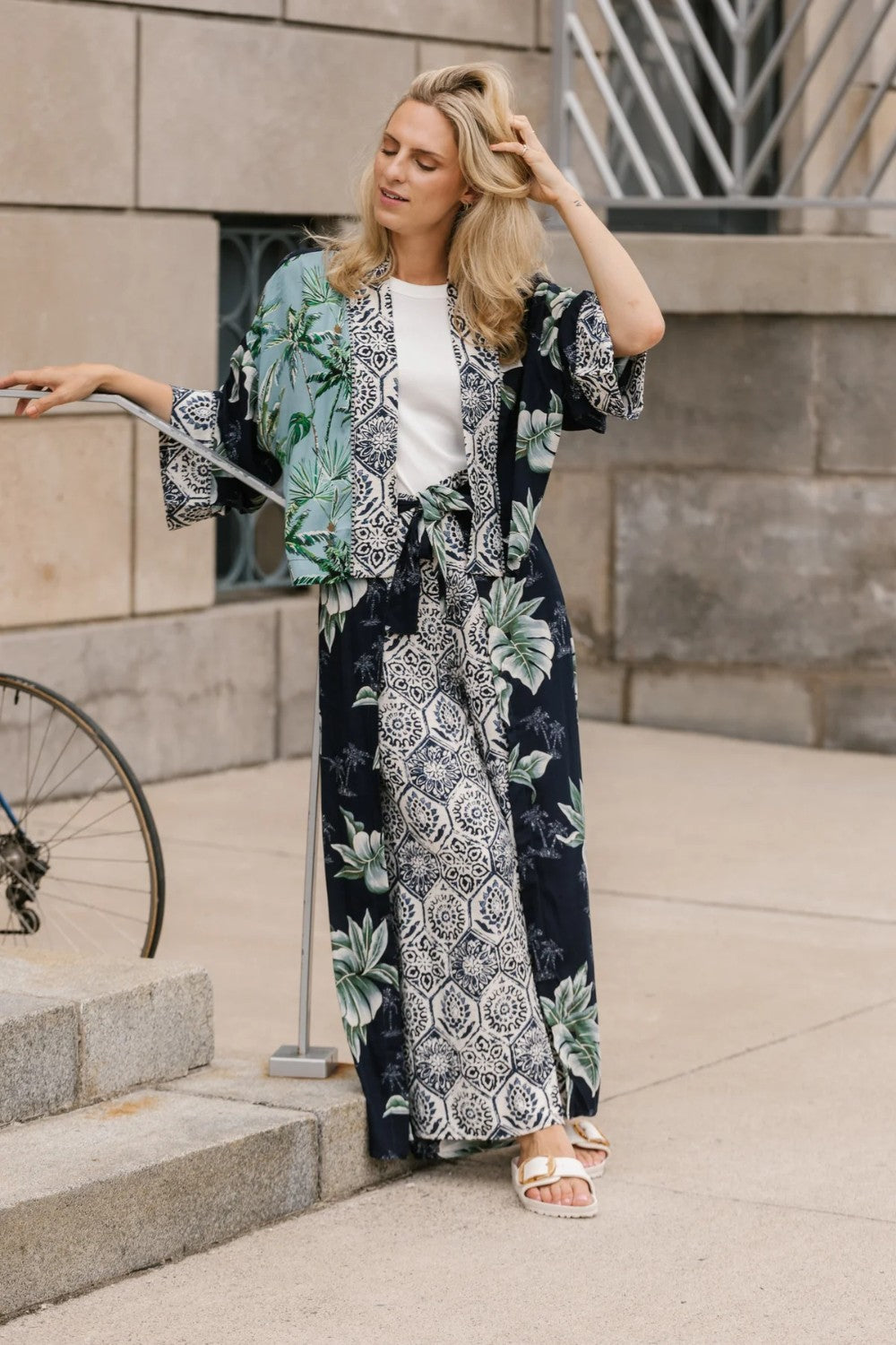 Woman wearing a palm print kimono standing on steps outdoors