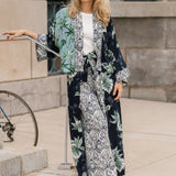 Woman wearing a palm print kimono-style outfit standing outdoors.