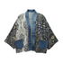 A mixed-media open-front cardigan featuring a blue denim collar, buttons, and front pockets, combined with a white damask patterned panel and a dark blue-gray ikat patterned panel.