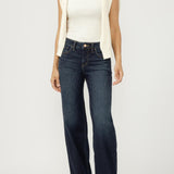Woman wearing a white top, cream vest, and dark blue jeans on a white background