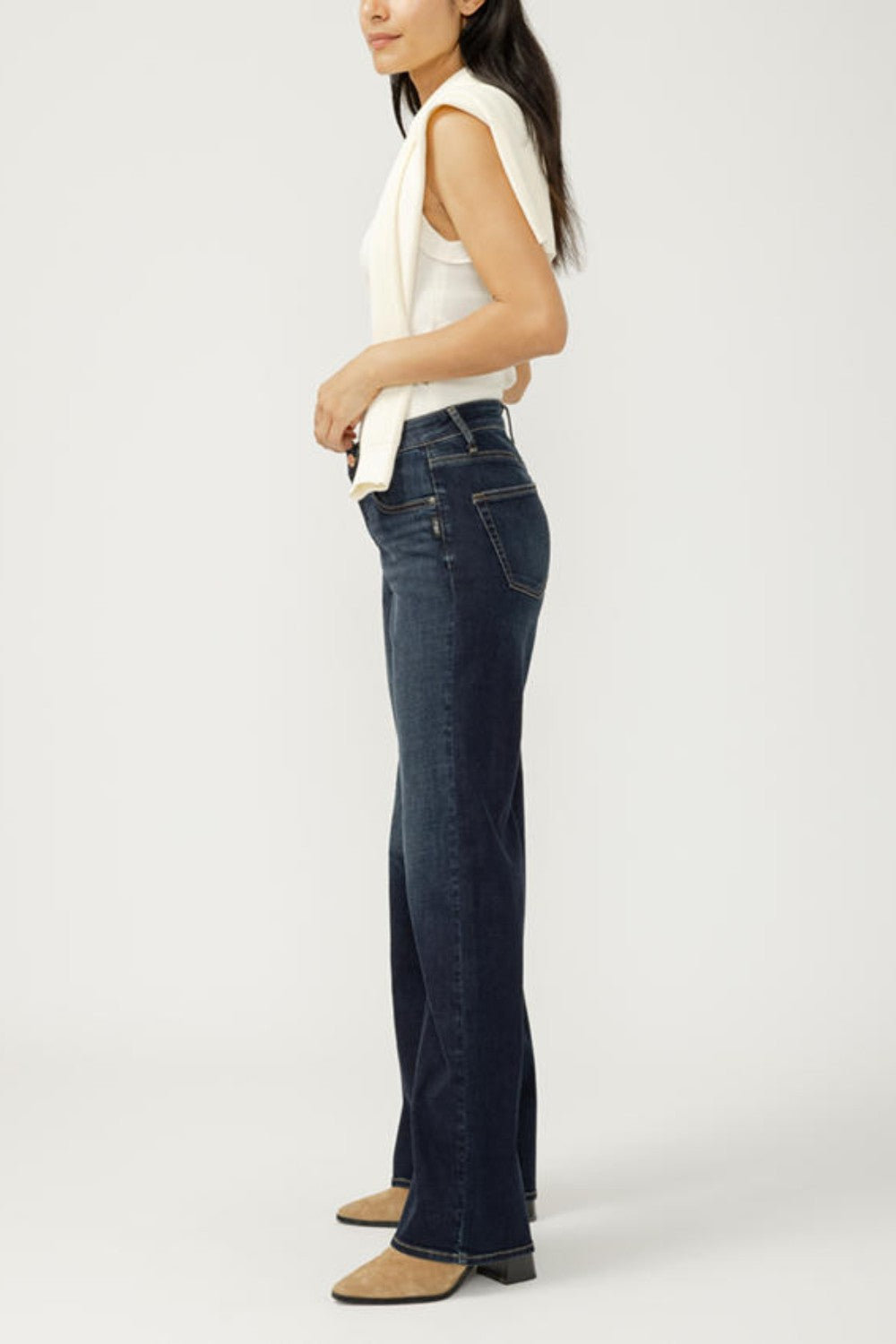 Woman wearing dark blue jeans and a white top on a white background