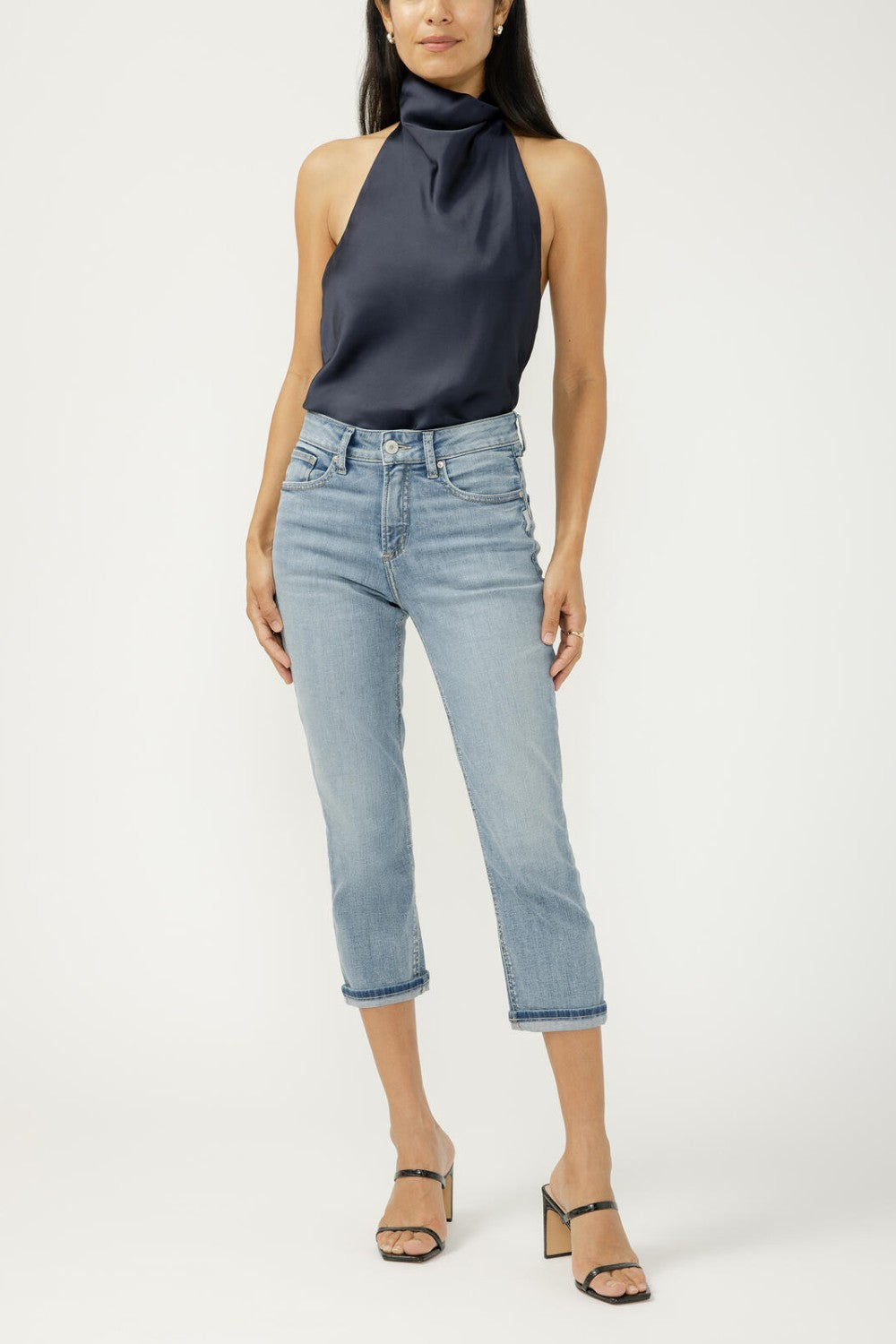 Woman wearing a navy halter top and light blue jeans on a white background