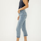 Woman wearing light blue jeans and a dark sleeveless top on a white background