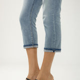 Person wearing light blue jeans and black heeled sandals on a white background