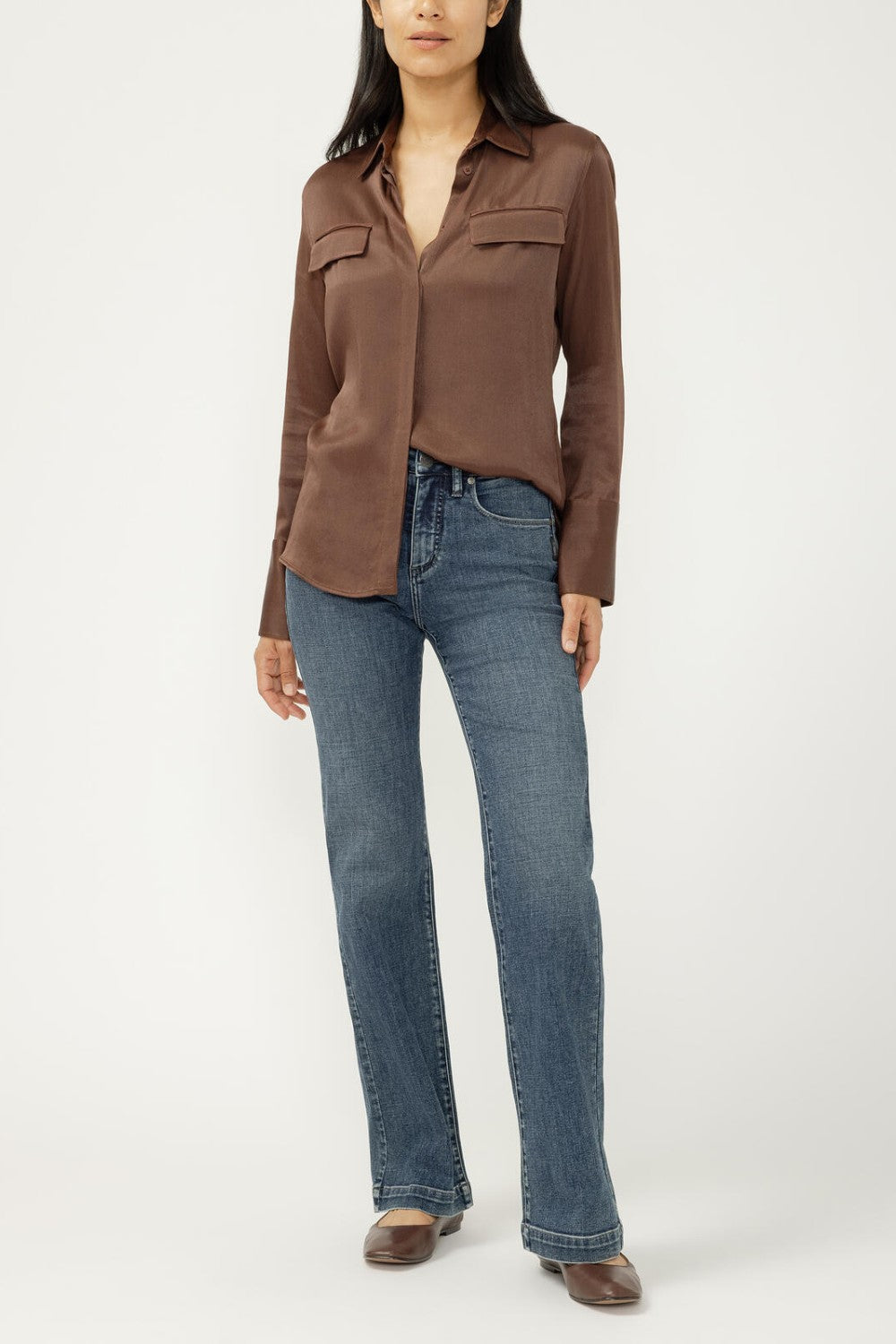 Woman wearing blue jeans with brown blouse on light background