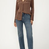 Woman wearing blue jeans with brown blouse on light background