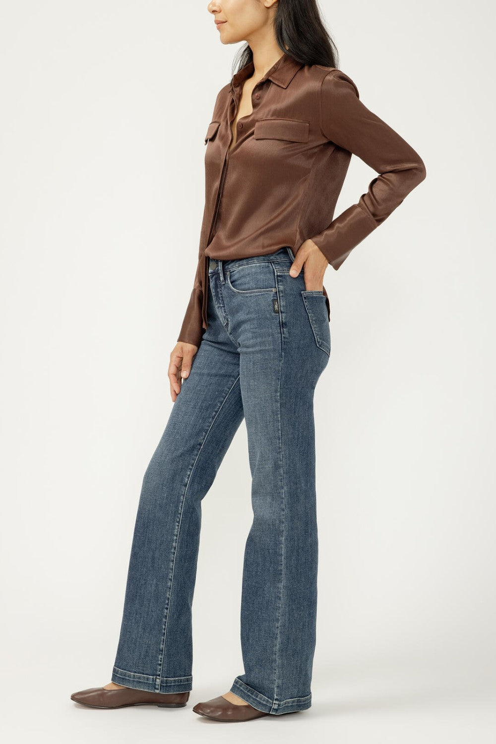 Woman wearing blue jeans with brown blouse on light background