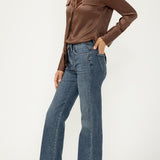 Woman wearing blue jeans with brown blouse on light background