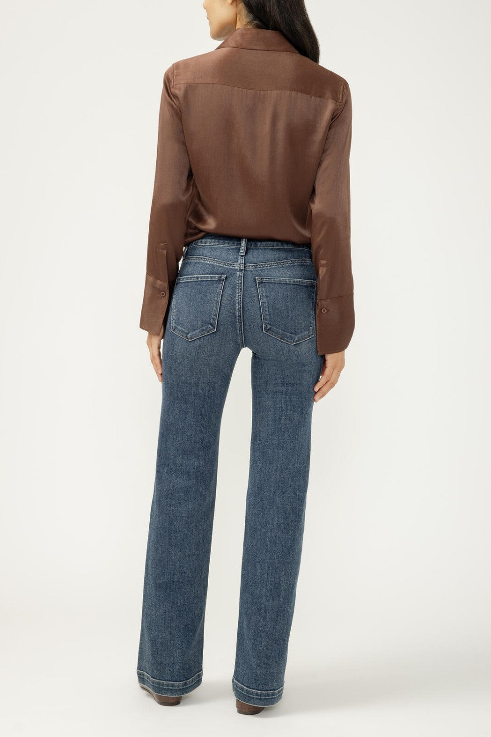 Woman wearing blue jeans with brown blouse on light background