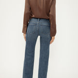 Woman wearing blue jeans with brown blouse on light background