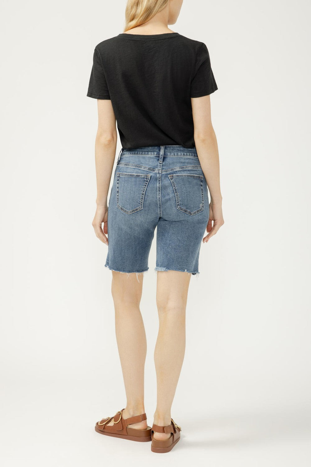 Person wearing a black t-shirt and blue denim shorts on a white background