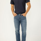 Man wearing a navy t-shirt and blue jeans on a white background