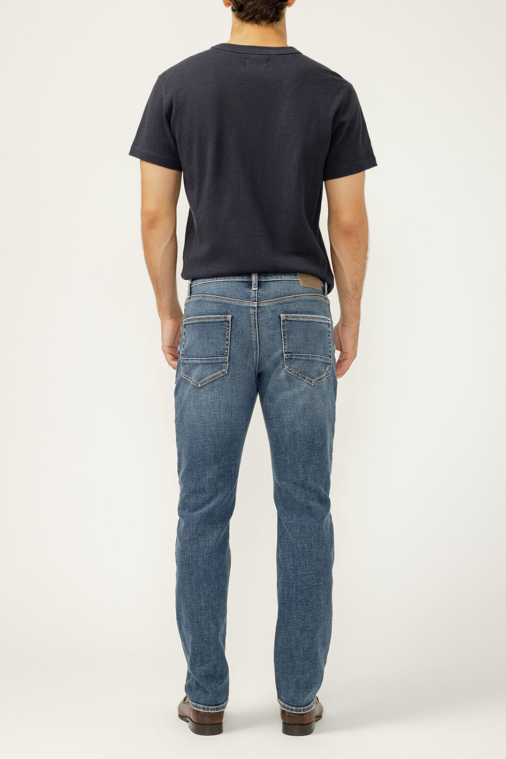 Person wearing blue jeans and a black t-shirt on a white background