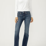 Woman wearing bootcut blue jeans with a white top on a light backdrop
