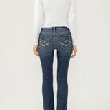 Woman wearing bootcut blue jeans with a white top on a light backdrop