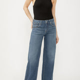 Person wearing a black sleeveless top and blue jeans on a white background