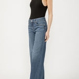 Person wearing a black sleeveless top and blue jeans on a white background