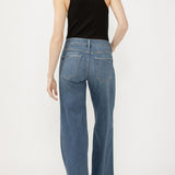 Person wearing blue jeans and a black sleeveless top on a white background