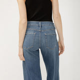 Person wearing blue jeans and a black sleeveless top on a white background