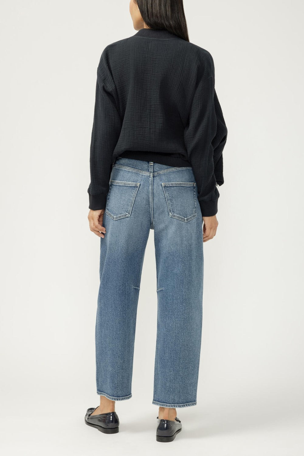 Person wearing blue jeans and a black sweater on a white background