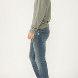 Person wearing a green sweatshirt and blue jeans on a white background