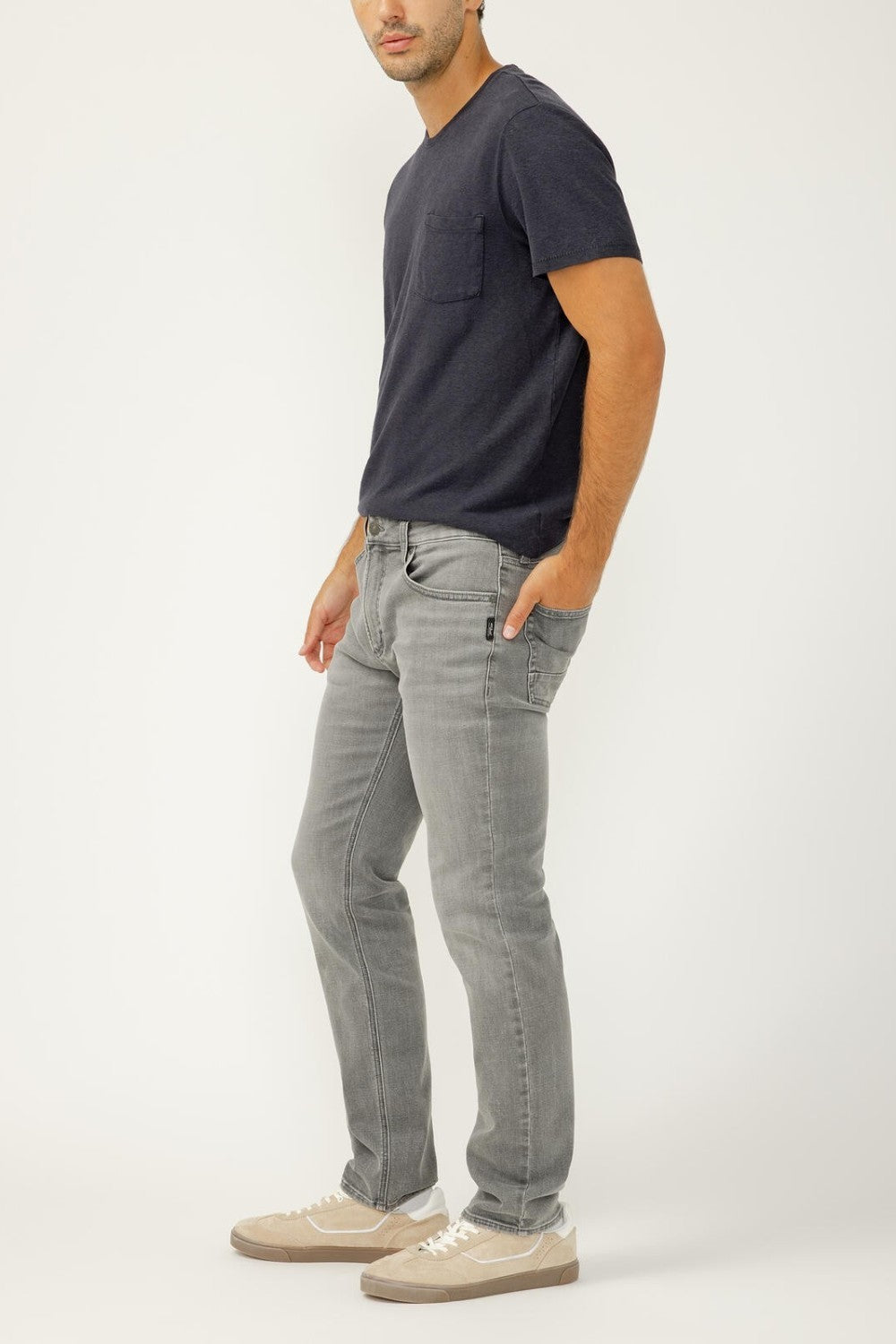 Man wearing a dark gray t-shirt and light gray jeans on a white background