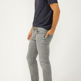 Man wearing a dark gray t-shirt and light gray jeans on a white background