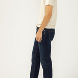 Man wearing a white polo shirt and dark blue jeans on a white background