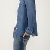 Man wearing a blue denim shirt and jeans on a white background